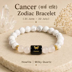 A Cancer zodiac bracelet made of white howlite and milky quartz beads with a central black cube bead featuring a gold Cancer zodiac symbol. The bracelet is displayed on a beige stone slab with decorative crystals and dried flowers in the background, with text overlays describing the product.