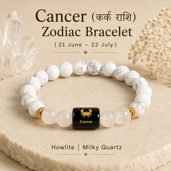 A Cancer zodiac bracelet made of white howlite and milky quartz beads with a central black cube bead featuring a gold Cancer zodiac symbol. The bracelet is displayed on a beige stone slab with decorative crystals and dried flowers in the background, with text overlays describing the product.