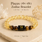 A Pisces Zodiac bracelet made of clear citrine beads and brown tiger eye beads, featuring a central black square bead with a gold Pisces symbol. The bracelet is displayed on a beige stone slab with decorative crystal and dried flower props, with text overlay detailing the zodiac and material information.