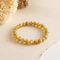 Cats Eye Lehsunia bracelet with honey-gold chatoyant beads on a cream backdrop with dried flowers – World of Oorja