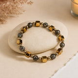 Double Power Money Attraction bracelet with faceted gold cubes and grey pyrite beads on a cream pebble – World of Oorja