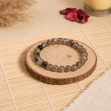 Dragon Vein agate bracelet with translucent grey-white crackle-veined beads on a rustic wood slice with pampas – World of Oorja