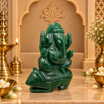 Jade Ganesh Ji murti in deep forest green on a marble altar with brass diya