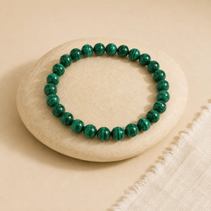 Malachite bracelet with deep green concentric banded beads on an off-white oval stone with ivory linen – World of Oorja