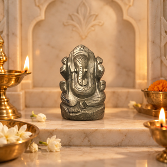 Pyrite Ganesh Ji murti in natural steel-grey stone on a marble altar with brass diya