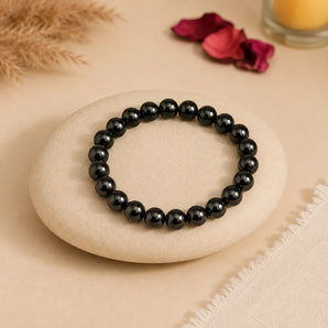 Shungite bracelet with opaque black beads and grey-green sheen on a cream river stone with pampas and rose petals – World of Oorja