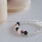 Close-up of a beaded bracelet with multicolored beads on a light background, featuring 'World of Oorja' branding.