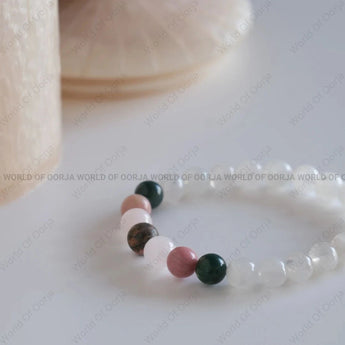 Close-up of a beaded bracelet with multicolored beads on a light background, featuring 'World of Oorja' branding.