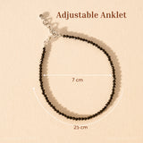 Black beaded anklet with adjustable strap on a beige background
