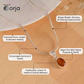 Silver necklace with a amber pendant on a textured surface, featuring Orja branding.