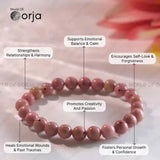 Pink beaded bracelet with therapeutic benefits labeled, branded 'World of Orja'.