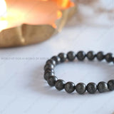 Grey beaded bracelet on a light surface with a blurred background