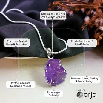 Purple amethyst pendant on a silver chain with labeled benefits, set against a dark fabric and dried flowers background.