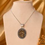 Raw Pyrite with a pendant on a mannequin bust against a gold fabric background