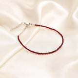Garnet beaded anklet on a beige satin background