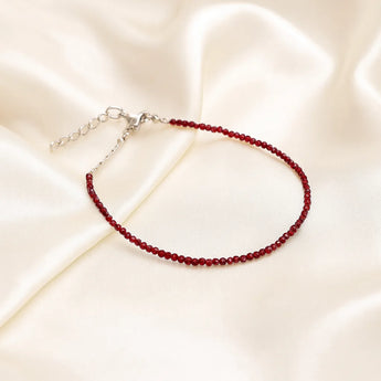 Garnet beaded anklet on a beige satin background