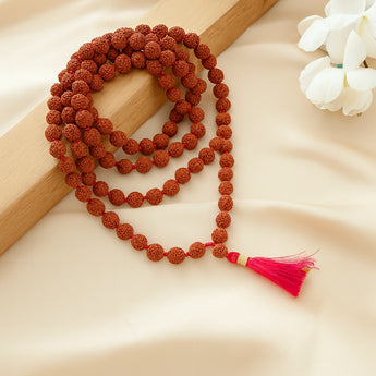 5 mukhi beaded necklace with a red tassel on a beige surface
