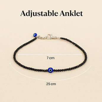 Adjustable anklet with black beads and blue evil eye charm on a beige background