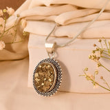 Raw pyrite with a gold pendant on a beige fabric background