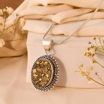Raw pyrite with a gold pendant on a beige fabric background