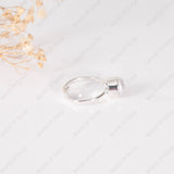 Silver ring on a light gray background with a small cluster of dried flowers.