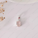 Pink gemstone pendant on a white background with dried flowers.