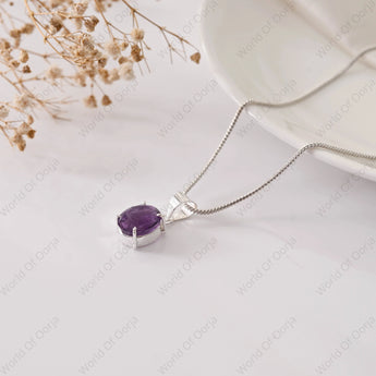 Silver necklace with a purple gemstone pendant on a light background