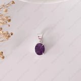 Purple gemstone pendant on a white background with dried flowers on the side