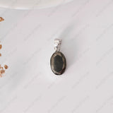 Silver pendant with a dark stone on a white background