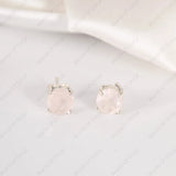 Pair of silver earrings with pink gemstones on a light gray background