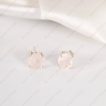 Pair of silver earrings with pink gemstones on a light gray background