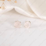 Pair of round earrings with a light pink gemstone on a white background