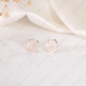 Pair of round earrings with a light pink gemstone on a white background