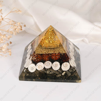 Pyramid-shaped decorative item with gold, black, and white elements on a white background