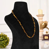 Necklace with brown beads on a black mannequin bust against a blurred indoor background