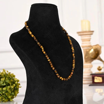 Necklace with brown beads on a black mannequin bust against a blurred indoor background