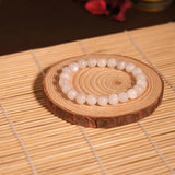 Pearl bracelet on a wooden coaster with a blurred candle in the background