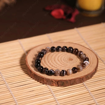 Beaded bracelet on a wooden coaster with a candle in the background