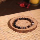 Beaded bracelet on a wooden coaster with a candle in the background
