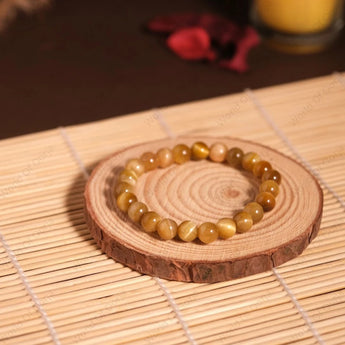 Beaded bracelet on a wooden coaster with a candle in the background