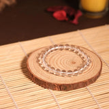 Clear glass coaster on a wooden slice with a candle in the background
