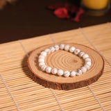 Pearl bracelet on a wooden coaster with a candle in the background