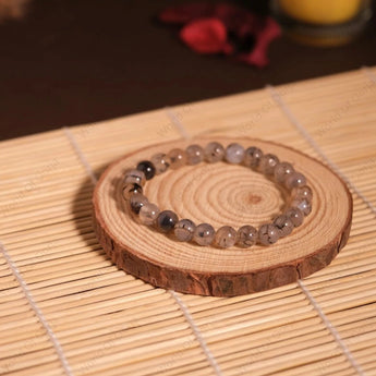 Beaded bracelet on a wooden coaster with a candle in the background