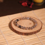 Beaded bracelet on a wooden coaster with a candle in the background