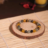 Bracelet with multicolored beads on a wooden coaster with a candle in the background
