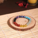 Colorful beaded bracelet on a wooden coaster with a candle in the background