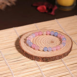 Beaded bracelet on a wooden coaster with a candle in the background