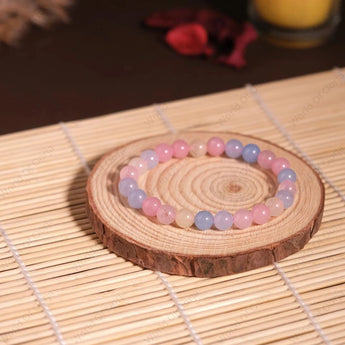 Beaded bracelet on a wooden coaster with a candle in the background