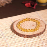 Yellow beaded bracelet on a wooden coaster with a blurred background