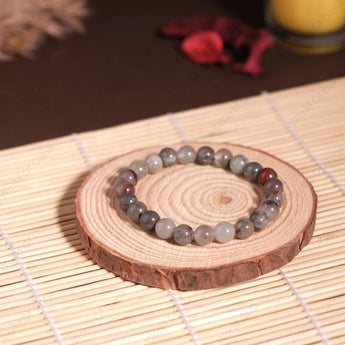 Beaded bracelet on a wooden coaster with a candle in the background